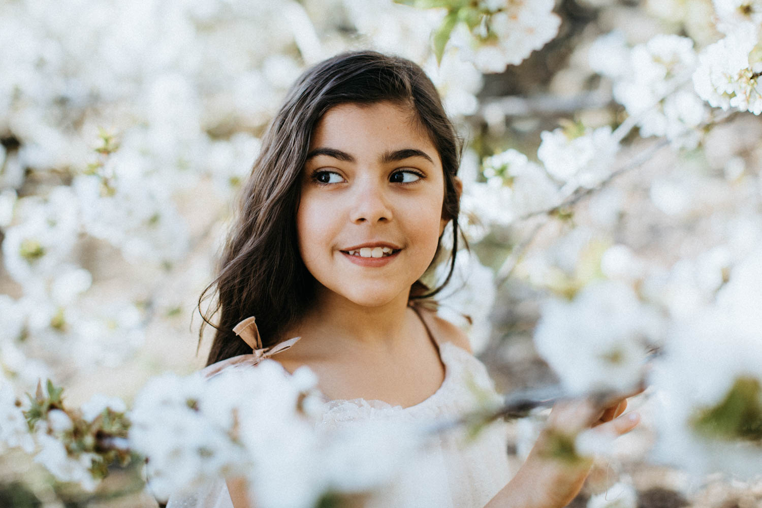 Retrato de una niña de comunión entre flores de cerezos